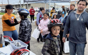 Bike giveaway recipients having helmets fitted