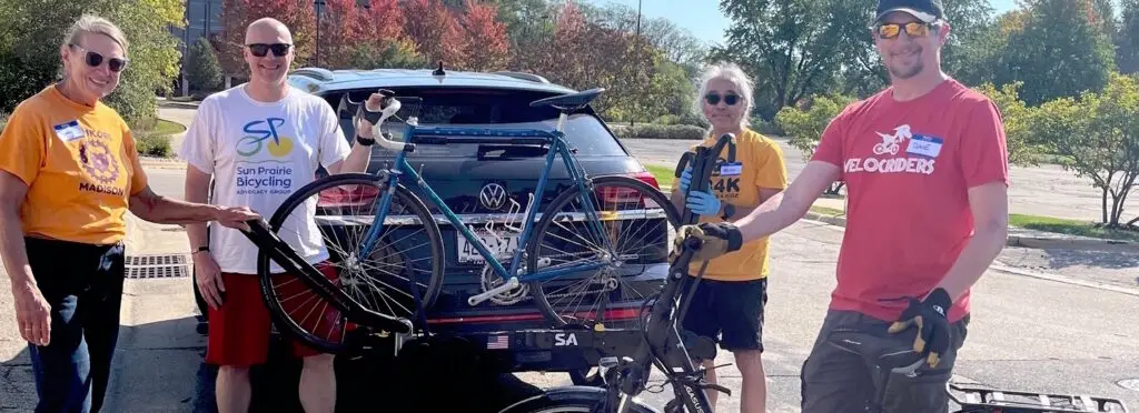 group of volunteers unloading bikes from a donor's car