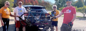 group of volunteers unloading bikes from a donor's car