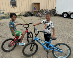 Two cute boys sitting on their bikes with big smiles.