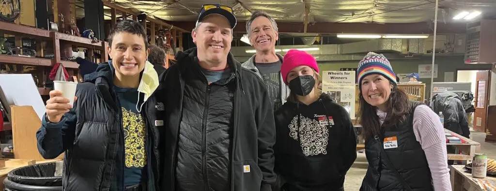 Group of smiling people standing in a bike shop and looking at the camera.