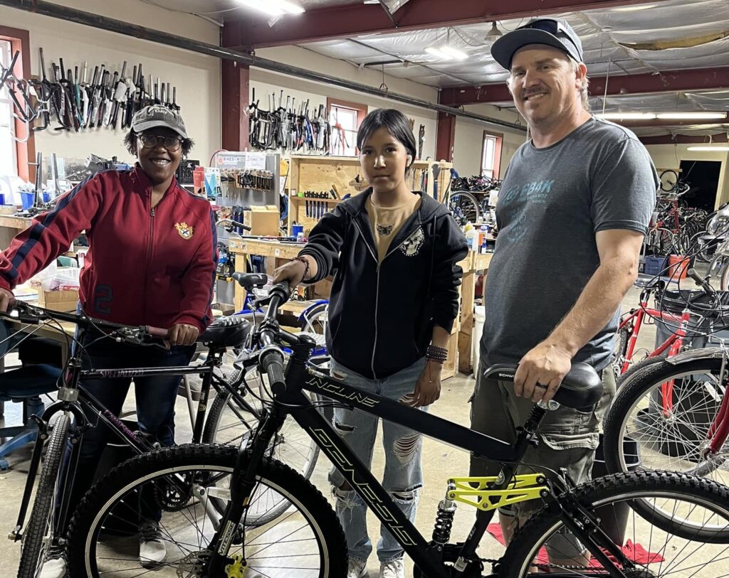 three people standing in front of bikes in the bike center