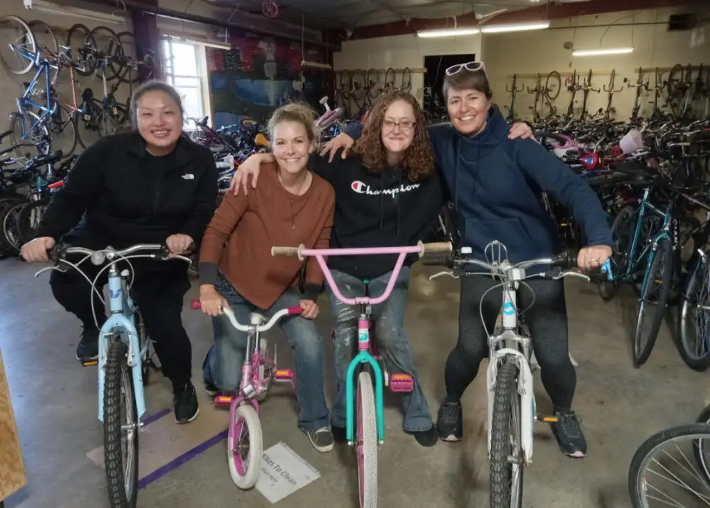 four women smiling and sitting on bikes