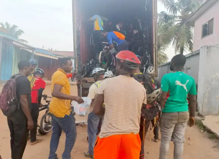 Group of people in Ghana unloading a shipping container of bikes from Madison, WI