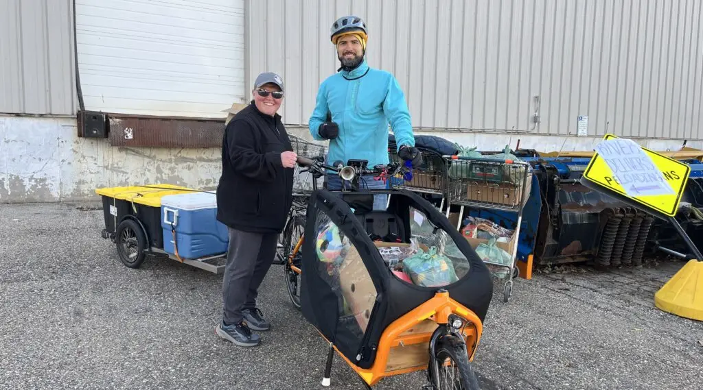 Jamie from River Food Pantry and Pepe from Bikes for Kids standing next to a cargo bike fully loaded with groceries
