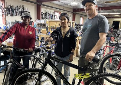 three people standing in front of bikes in the bike center