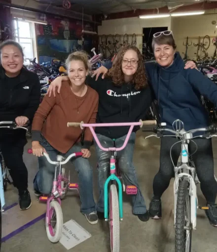 four women smiling and sitting on bikes