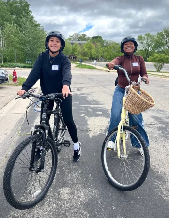two young black girls sitting on bikes with smiles of joy and pride